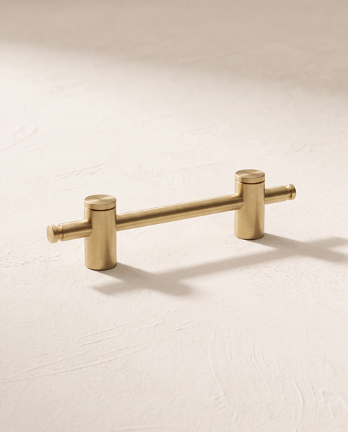 Axis longline brushed brass pull, packshot on warm ivory plaster